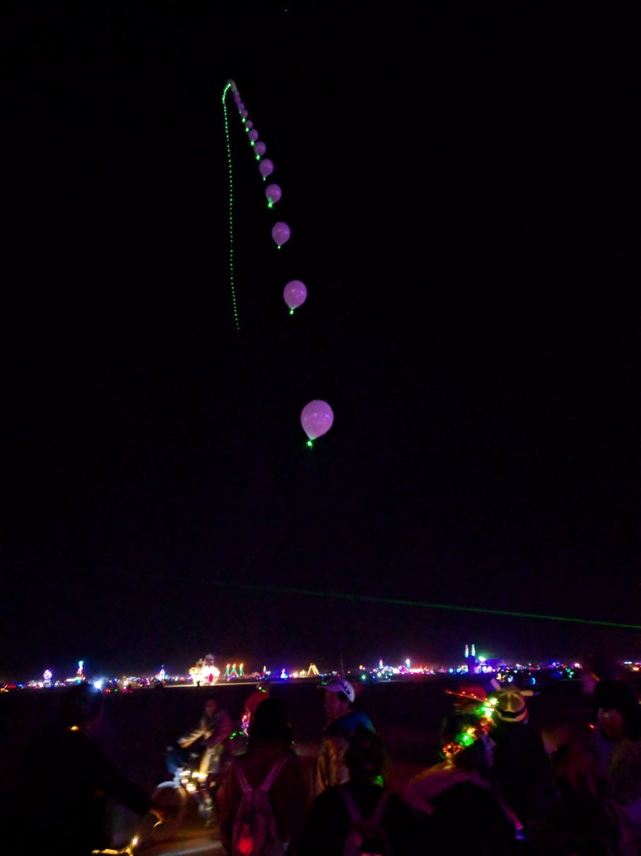 A chain of helium baloon reaching far into the night baloons